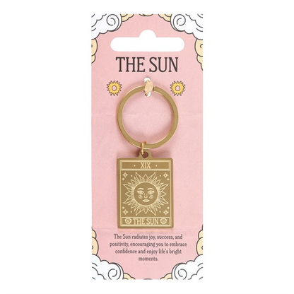 Gold keychain with 'The Sun' design on a pink packaging card.