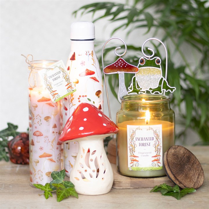 Candle and decorative items with a 'Enchanted Forest' theme on a wooden surface.