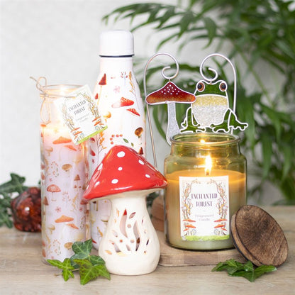 Candle and decorative items with a 'Enchanted Forest' theme on a wooden surface.