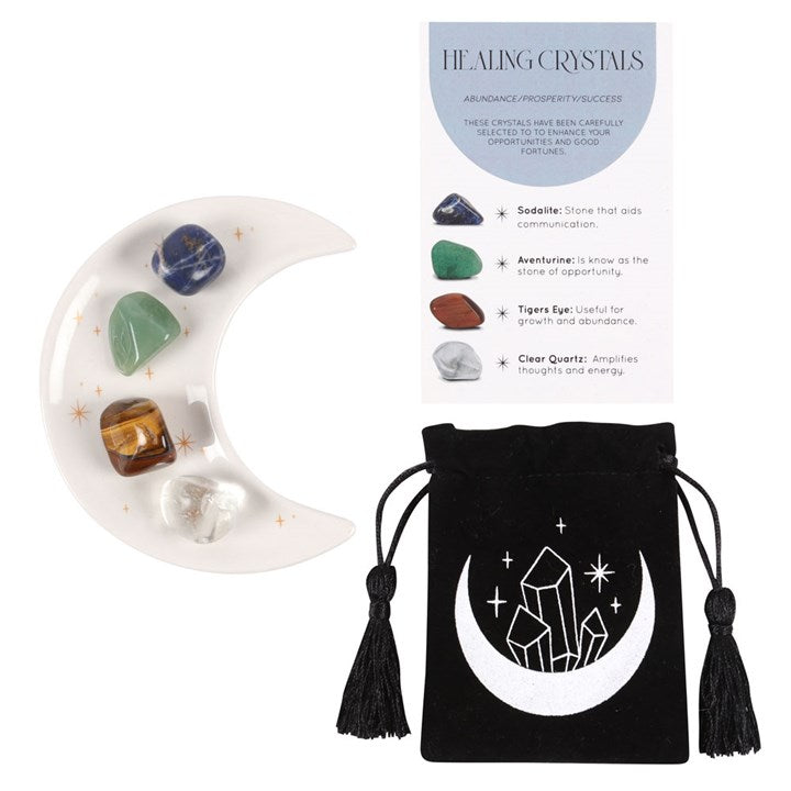 Healing crystals set with a moon-shaped tray, stones, and a black drawstring bag on a white background.