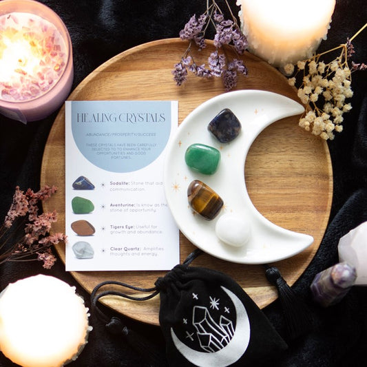Healing crystals on a moon-shaped dish with a card explaining crystal properties on a wooden tray.