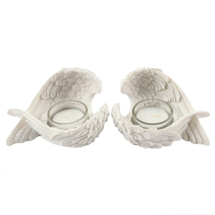 Two white ceramic angel wing candle holders on a white background