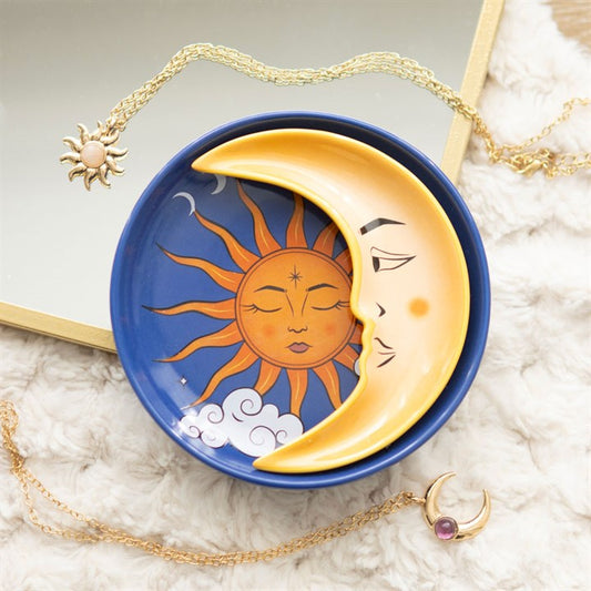 Decorative dish with sun and moon design on a textured surface with jewelry.