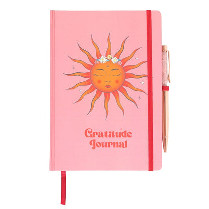 Pink gratitude journal with a sun illustration on a white background