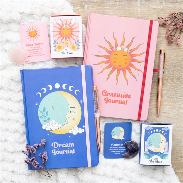 Two journals, one blue and one pink, with celestial designs on a textured surface.
