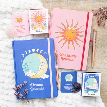 Two journals, one blue and one pink, with celestial designs on a textured surface.