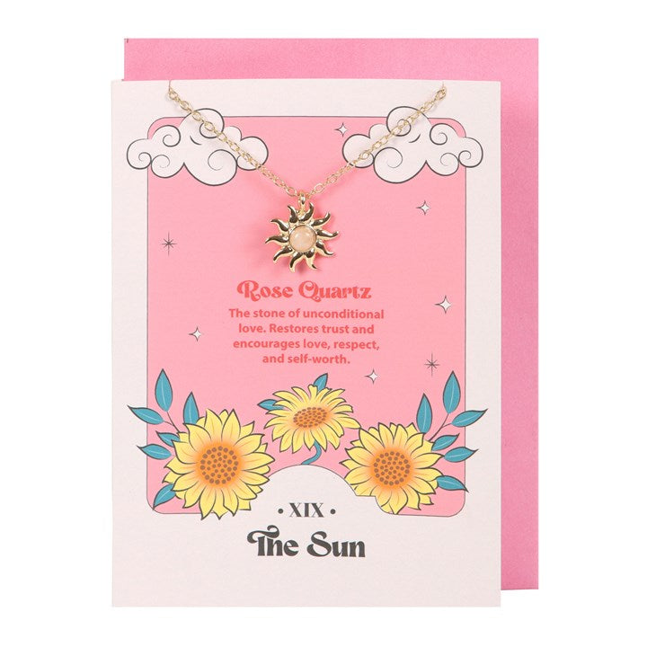 Necklace with sun pendant on a pink card with floral designs