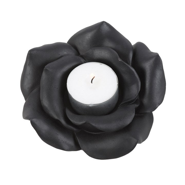Black rose-shaped candle holder with a white candle on a white background