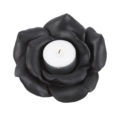 Black rose-shaped candle holder with a white candle on a white background