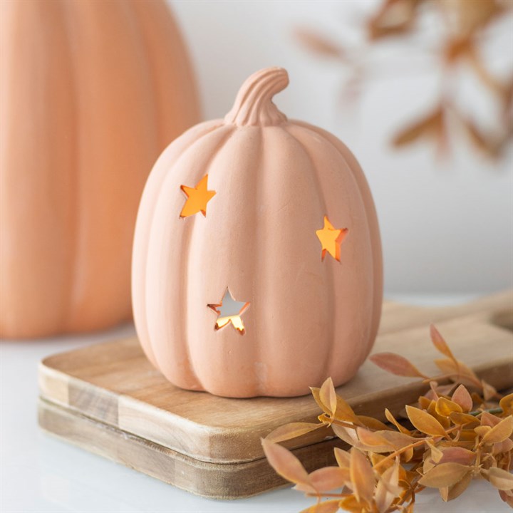 Decorative pumpkin with star cutouts on a wooden stand with a blurred background