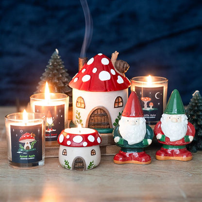 Decorative candles with mushroom and gnome designs on a wooden surface.
