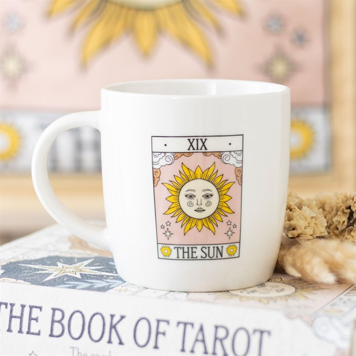 White mug with 'The Sun' tarot card design on a book titled 'The Book of Tarot'.