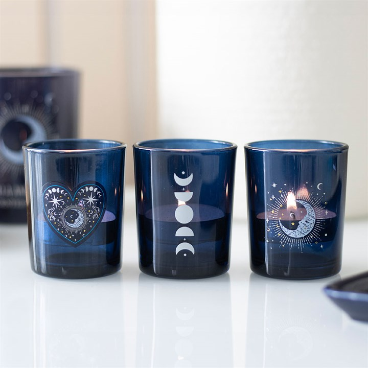Three blue candle holders with celestial designs on a white surface.