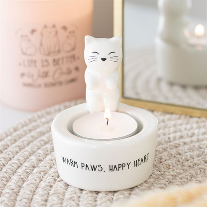 White cat sitting on edge of tealight candle holder